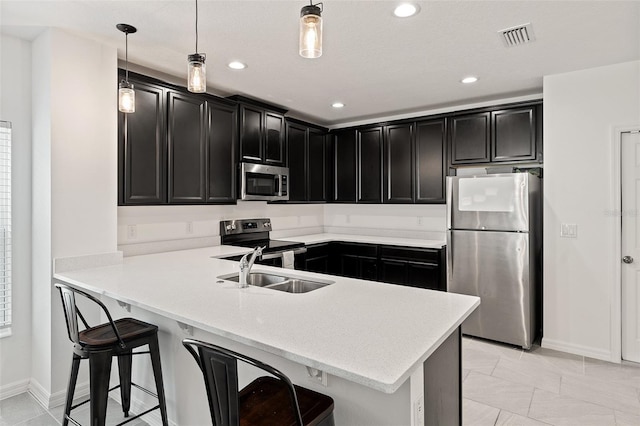 9356 St Therese St, Groveland, FL 34736 - kitchen featuring stainless steel appliances, dark cabinets, a peninsula, a sink, and baseboards