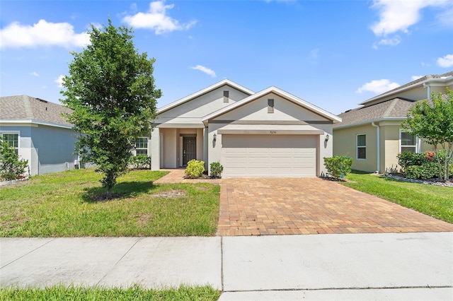 9356 St Therese St, Groveland, FL 34736 - ranch-style house featuring decorative driveway, an attached garage, a front yard, and stucco siding