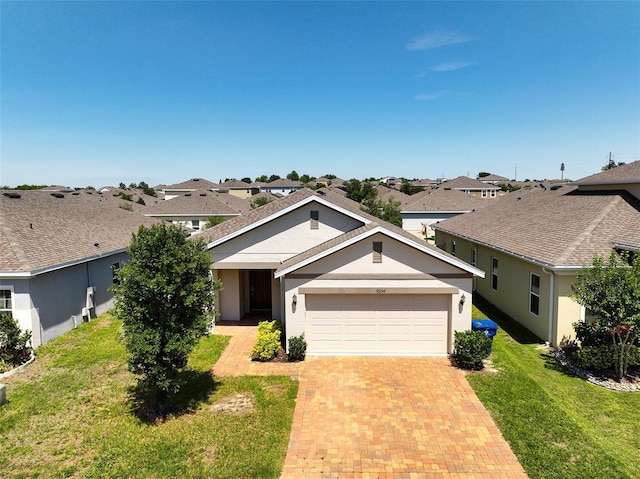 9356 St Therese St, Groveland, FL 34736 - view of front of house featuring a garage, a front lawn, decorative driveway, stucco siding, and a residential view