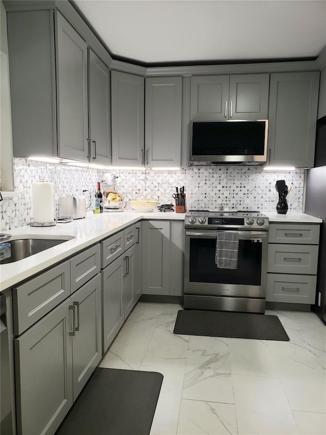 983 Bucksaw Pl, Longwood, FL 32750 - kitchen with appliances with stainless steel finishes, gray cabinetry, light marble finish floors, light countertops, and tasteful backsplash