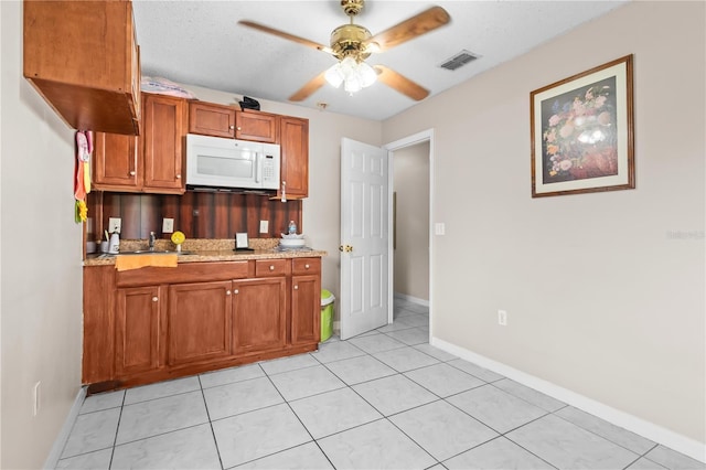 14 Sequoia Way, Kissimmee, FL 34758 - kitchen with white microwave, brown cabinets, a ceiling fan, baseboards, and light tile patterned floors