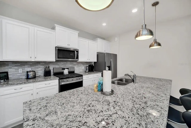 kitchen with appliances with stainless steel finishes, a sink, white cabinets, decorative backsplash, and light stone counters