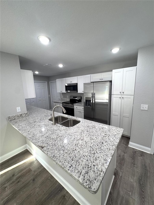 kitchen featuring appliances with stainless steel finishes, a sink, baseboards, a peninsula, and dark wood-type flooring