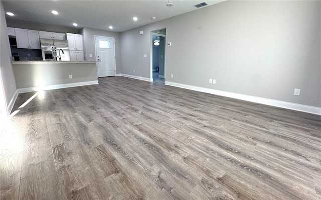 unfurnished living room with wood finished floors, baseboards, and recessed lighting