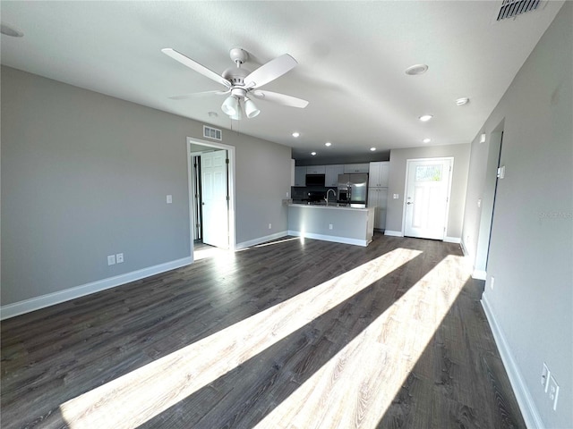 unfurnished living room with baseboards, dark wood-style flooring, and recessed lighting