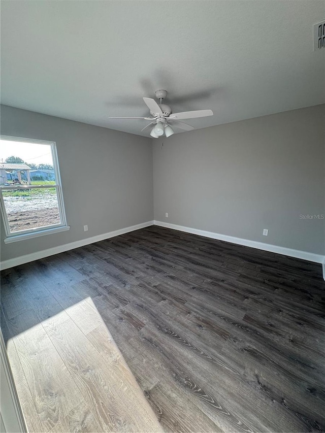 empty room featuring dark wood finished floors, baseboards, and ceiling fan