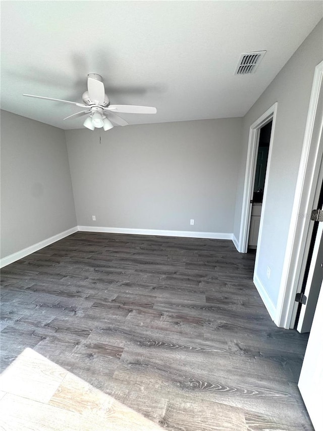 empty room with dark wood-type flooring, a ceiling fan, and baseboards