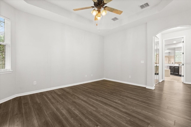 1601 Stargazer Ter, Sanford, FL 32771 - empty room with arched walkways, a tray ceiling, dark wood-style floors, and plenty of natural light