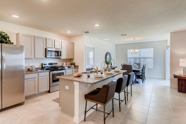 5169 Masser Rd, Saint Cloud, FL 34772 - kitchen featuring stainless steel appliances, a sink, a breakfast bar area, a center island with sink, and a chandelier