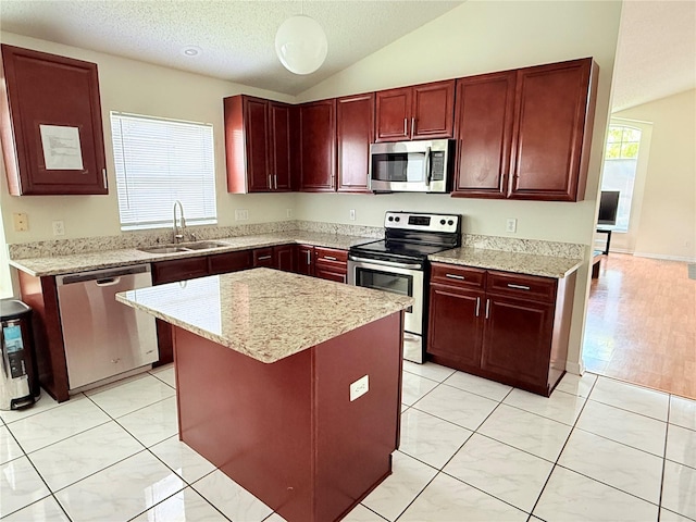 12756 Maribou Cir, Orlando, FL 32828 - kitchen featuring stainless steel appliances, reddish brown cabinets, lofted ceiling, a center island, and light stone counters