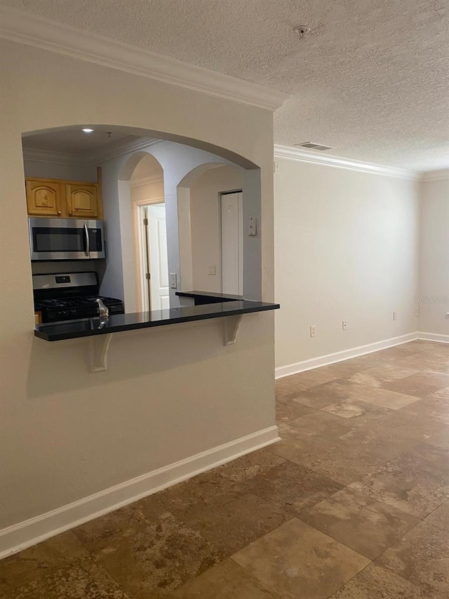 2007 Dixie Belle Dr Unit 2007M, Orlando, FL 32812 - kitchen featuring stainless steel appliances, a kitchen bar, crown molding, baseboards, and brown cabinetry