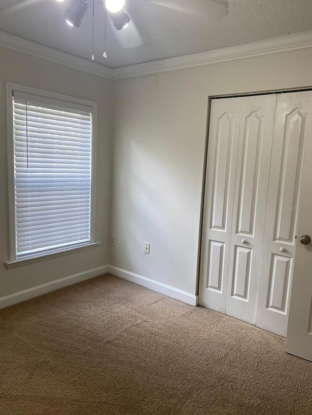 2007 Dixie Belle Dr Unit 2007M, Orlando, FL 32812 - unfurnished bedroom with carpet, crown molding, a closet, baseboards, and a ceiling fan