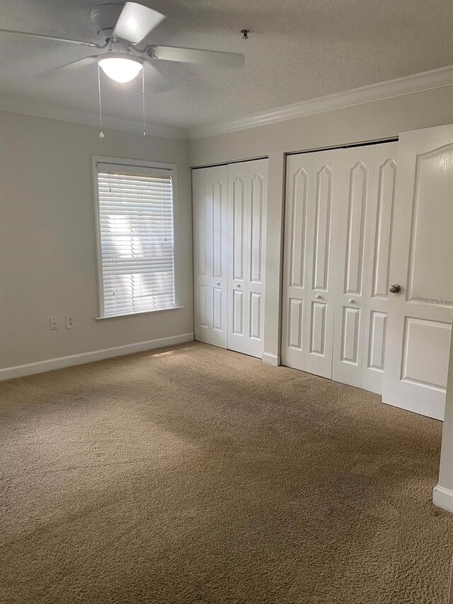 2007 Dixie Belle Dr Unit 2007M, Orlando, FL 32812 - unfurnished bedroom with two closets, carpet, crown molding, baseboards, and a textured ceiling