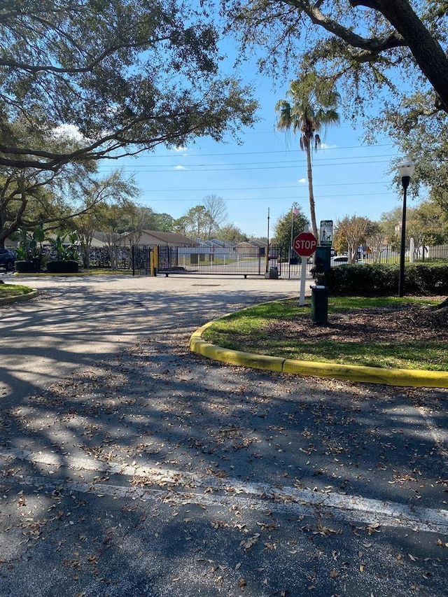 2007 Dixie Belle Dr Unit 2007M, Orlando, FL 32812 - view of asphalt street featuring traffic signs, a gate, and curbs