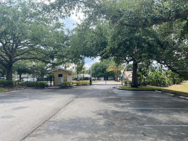 2007 Dixie Belle Dr Unit 2007M, Orlando, FL 32812 - view of asphalt road featuring a gate, curbs, a gated entry, and street lighting
