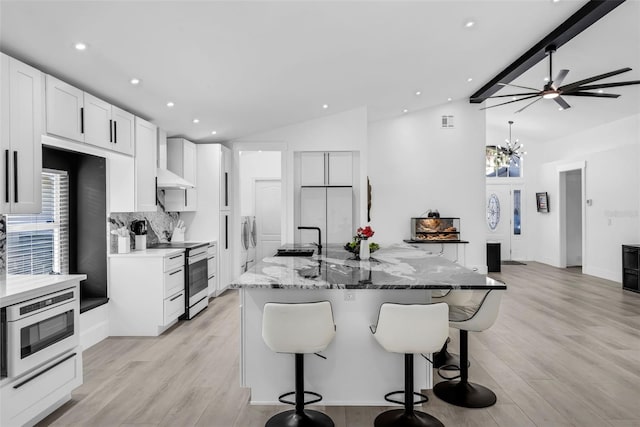 2520 Oakington St, Winter Garden, FL 34787 - kitchen featuring stainless steel range with electric stovetop, vaulted ceiling, tasteful backsplash, a sink, and a kitchen breakfast bar