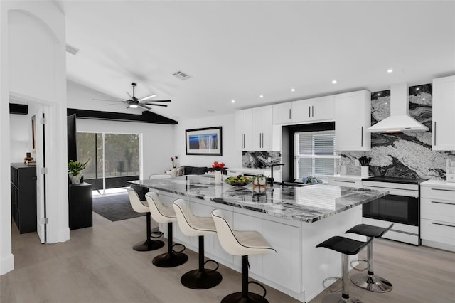2520 Oakington St, Winter Garden, FL 34787 - kitchen with range with electric cooktop, wall chimney range hood, tasteful backsplash, white cabinets, and a kitchen island
