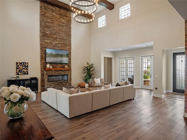 20199 Sweetwood Ln, Clermont, FL 34715 - living area with a towering ceiling, a chandelier, a stone fireplace, wood finished floors, and baseboards