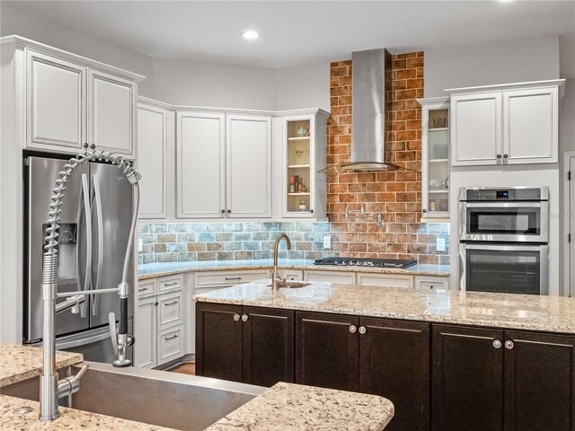 20199 Sweetwood Ln, Clermont, FL 34715 - kitchen featuring appliances with stainless steel finishes, wall chimney exhaust hood, white cabinetry, a sink, and glass insert cabinets