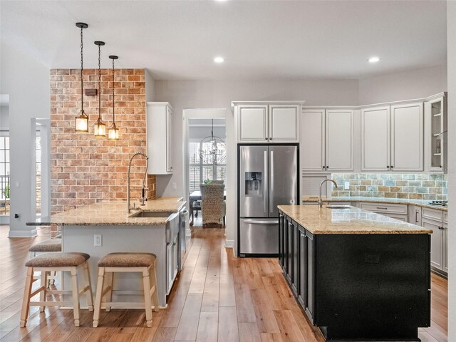 20199 Sweetwood Ln, Clermont, FL 34715 - kitchen featuring stainless steel refrigerator with ice dispenser, a sink, backsplash, light wood finished floors, and hanging light fixtures