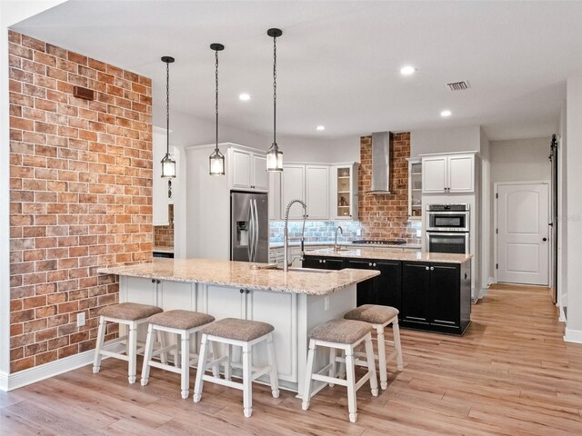 20199 Sweetwood Ln, Clermont, FL 34715 - kitchen featuring stainless steel appliances, wall chimney exhaust hood, a sink, a kitchen island with sink, and baseboards