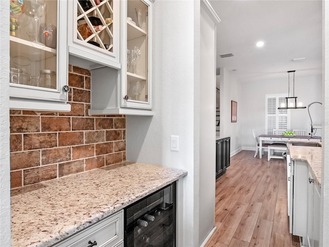 20199 Sweetwood Ln, Clermont, FL 34715 - kitchen featuring decorative backsplash, light wood-style flooring, light stone countertops, and glass insert cabinets