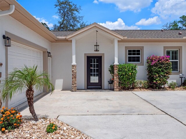 20199 Sweetwood Ln, Clermont, FL 34715 - doorway to property with stucco siding, driveway, an attached garage, and a shingled roof