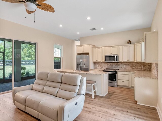 20199 Sweetwood Ln, Clermont, FL 34715 - kitchen with stainless steel appliances, open floor plan, backsplash, light wood finished floors, and a ceiling fan