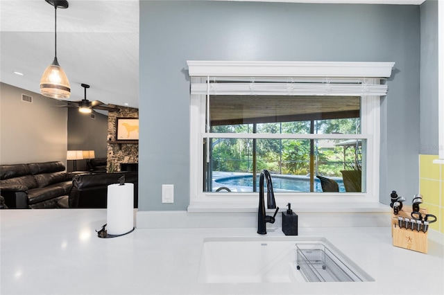 5370 Whispering Pine Cir, Saint Cloud, FL 34771 - kitchen featuring a sink, a ceiling fan, a fireplace, pendant lighting, and light countertops