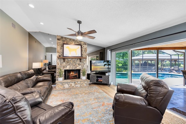5370 Whispering Pine Cir, Saint Cloud, FL 34771 - living area with ceiling fan, lofted ceiling, a textured ceiling, a stone fireplace, and light wood finished floors