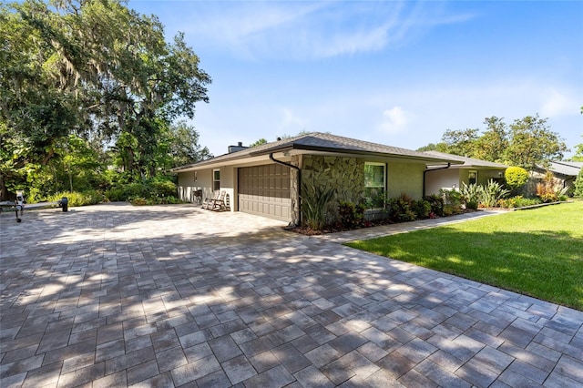 5370 Whispering Pine Cir, Saint Cloud, FL 34771 - view of side of property featuring decorative driveway, a garage, a yard, a chimney, and stone siding