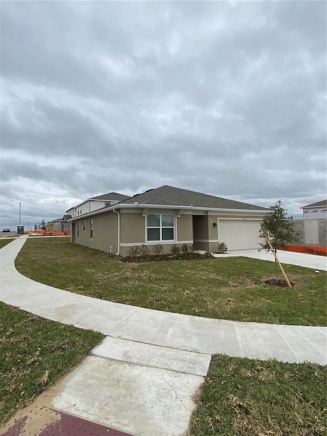 single story home with concrete driveway, a front lawn, a garage, and stucco siding