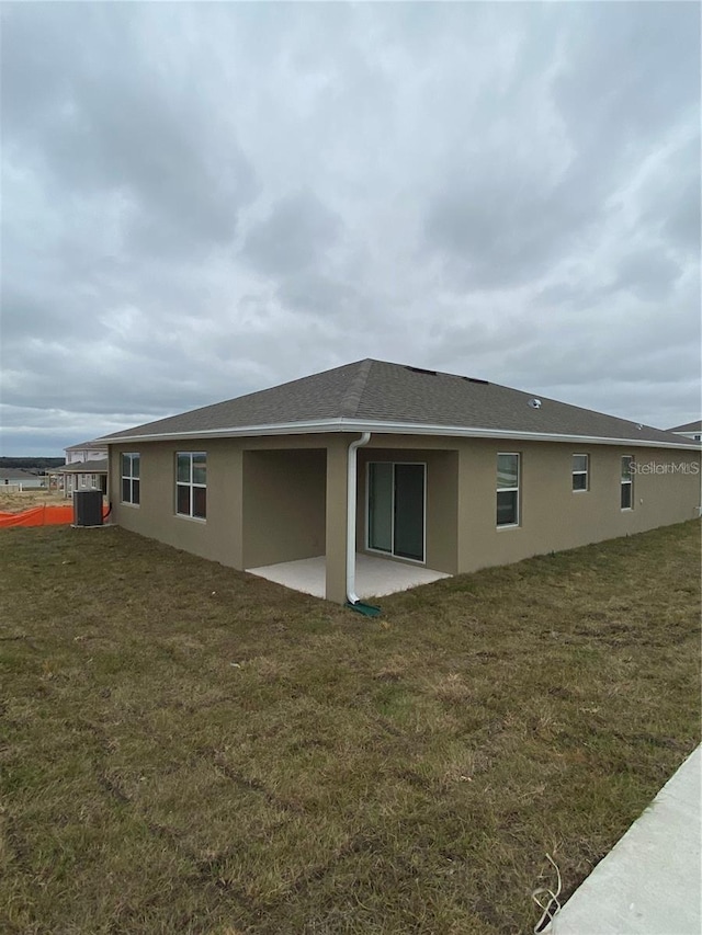 back of property featuring stucco siding, a patio area, and a lawn