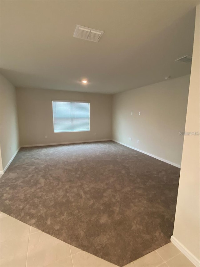 carpeted empty room with baseboards and tile patterned flooring