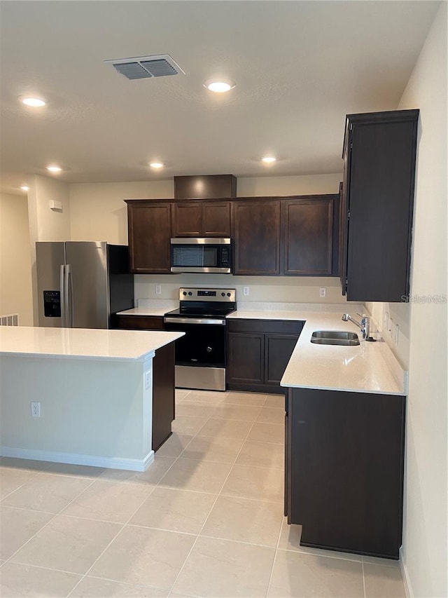 kitchen featuring appliances with stainless steel finishes, a sink, light countertops, dark brown cabinetry, and recessed lighting
