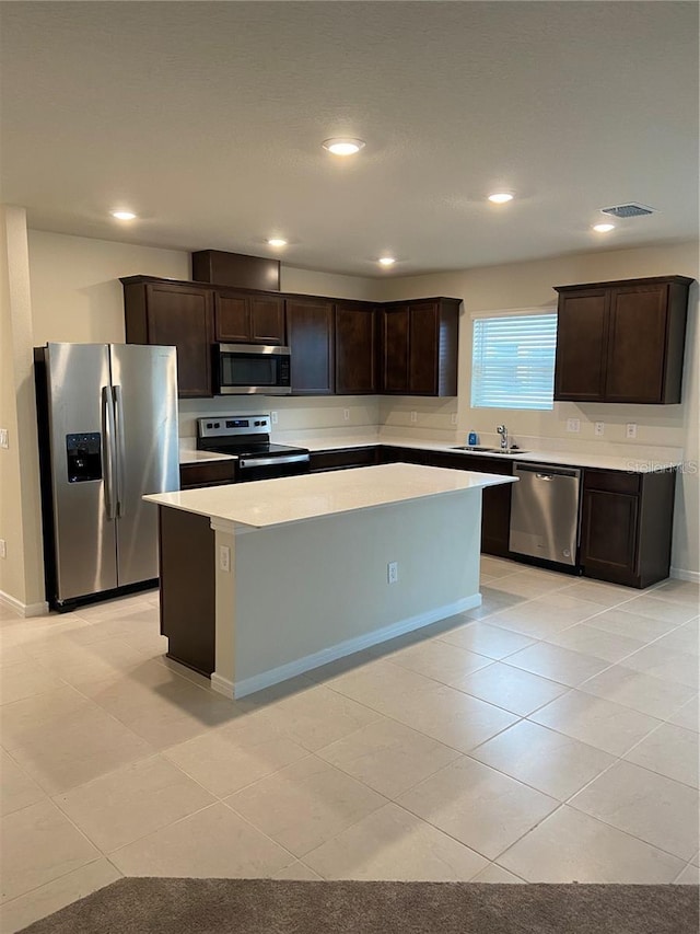 kitchen with stainless steel appliances, dark brown cabinets, a sink, and recessed lighting