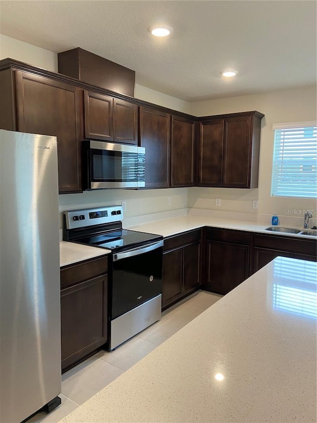 kitchen with appliances with stainless steel finishes, a sink, dark brown cabinetry, and recessed lighting