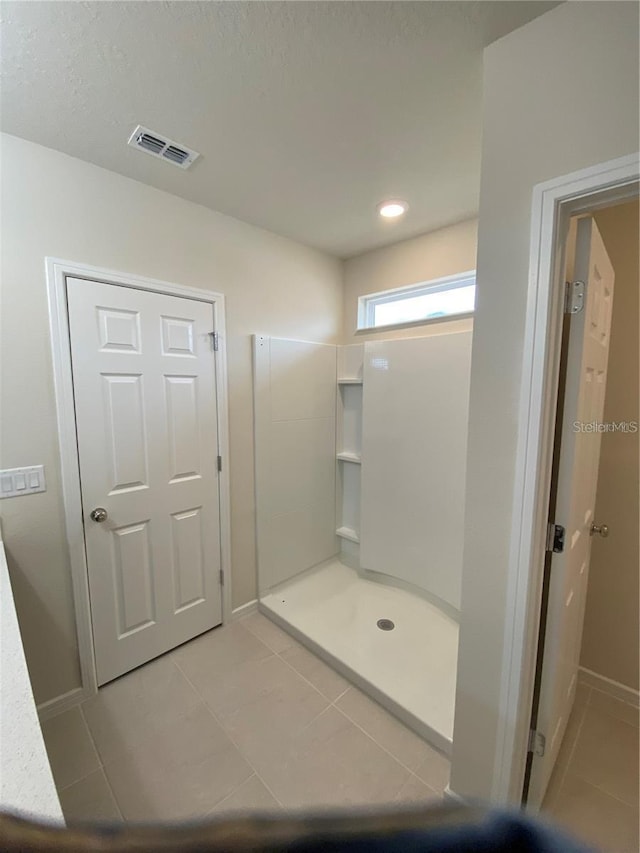 full bath featuring tile patterned flooring, a walk in shower, baseboards, and a textured ceiling