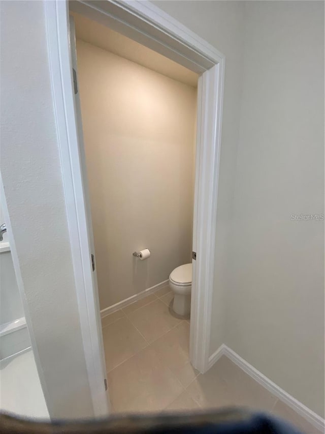 bathroom featuring toilet, tile patterned floors, and baseboards