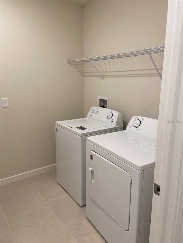 laundry area with washing machine and clothes dryer, baseboards, and light tile patterned flooring