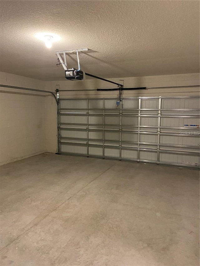 garage with a garage door opener and concrete block wall