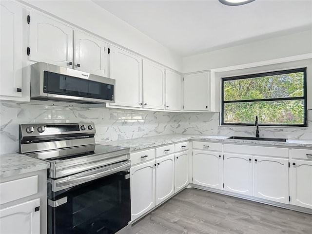 43 Lake Court Loop, Ocala, FL 34472 - kitchen featuring appliances with stainless steel finishes, a sink, white cabinetry, tasteful backsplash, and light wood-style flooring