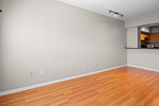 2411 W Horatio St Unit 537, Tampa, FL 33609 - unfurnished living room with light wood finished floors, baseboards, and track lighting
