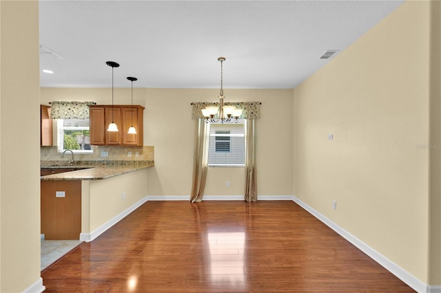 3677 Serena Ln, Clermont, FL 34711 - kitchen with wood finished floors, brown cabinetry, a chandelier, and decorative backsplash