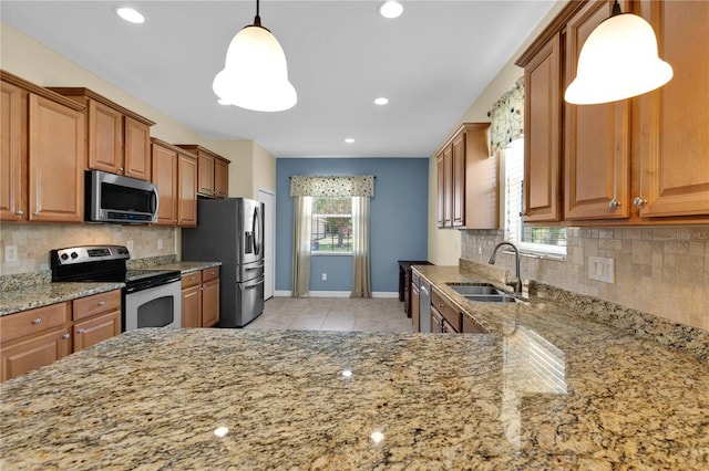 3677 Serena Ln, Clermont, FL 34711 - kitchen featuring stainless steel appliances, a sink, brown cabinetry, light stone countertops, and baseboards