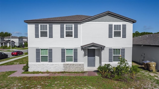 view of front of home with stone siding and a front lawn