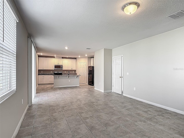 kitchen with appliances with stainless steel finishes, open floor plan, a kitchen island with sink, baseboards, and recessed lighting