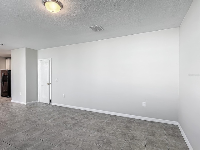 spare room featuring baseboards, a textured ceiling, and tile patterned flooring