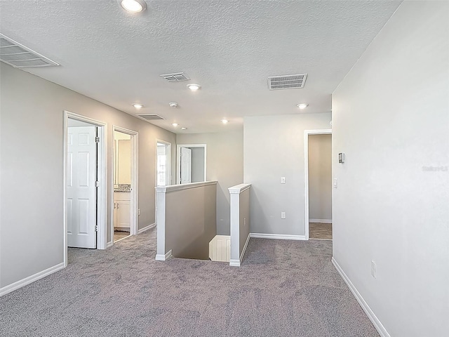 carpeted spare room featuring a textured ceiling, baseboards, and recessed lighting
