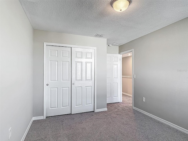 unfurnished bedroom with carpet flooring, baseboards, a closet, and a textured ceiling